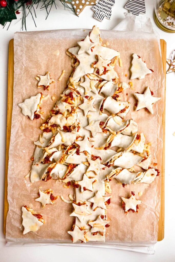 Unbaked puff pastry Christmas tree on a wooden board.