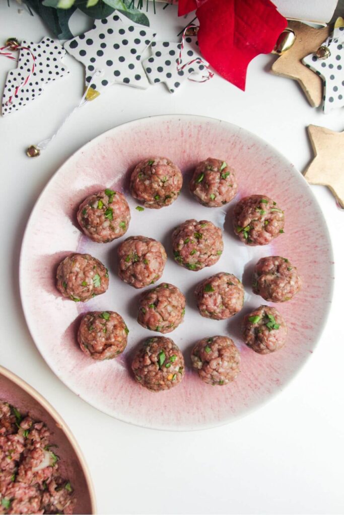 Rolled meatballs on a pink plate.