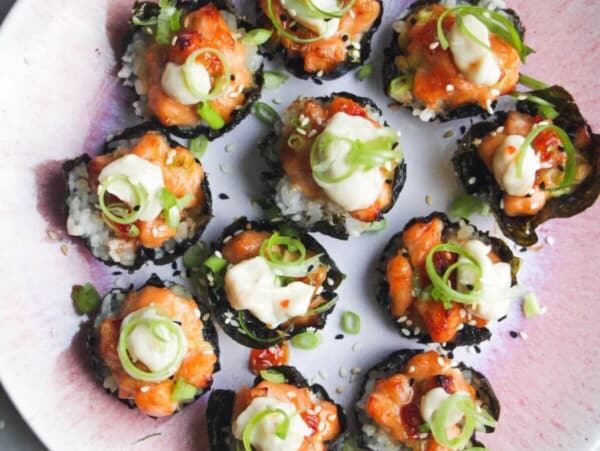Salmon sushi cups on a pink plate, with aioli and sweet chilli on the side.