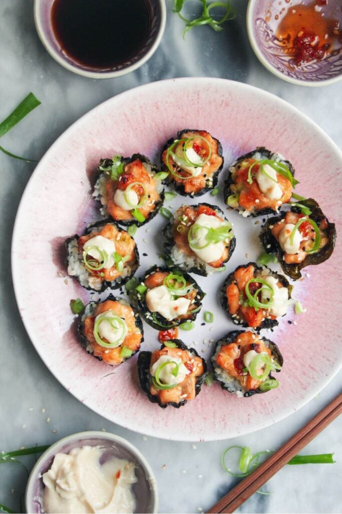 Salmon sushi cups on a pink plate, with aioli and sweet chilli on the side.