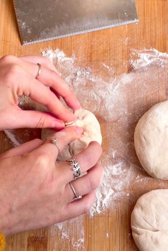 Hands sealing dough stuffed with cranberry suace and brie.