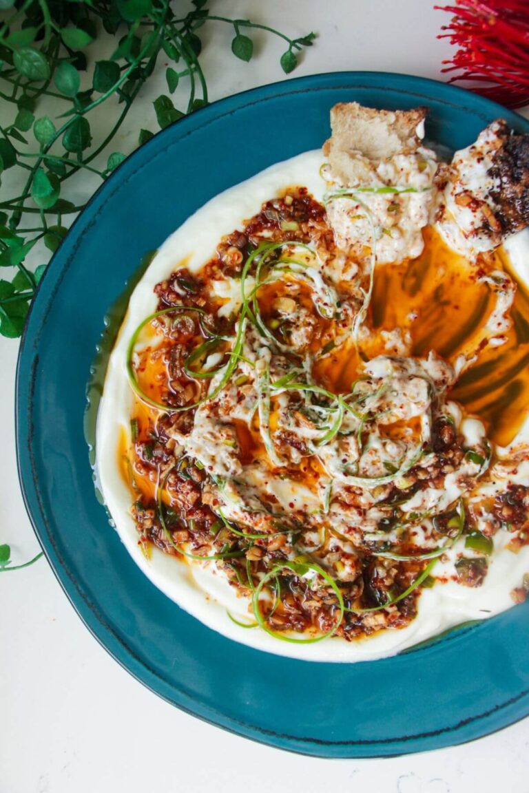 Sizzling oil on top of creamy Greek yogurt on a teal plate.