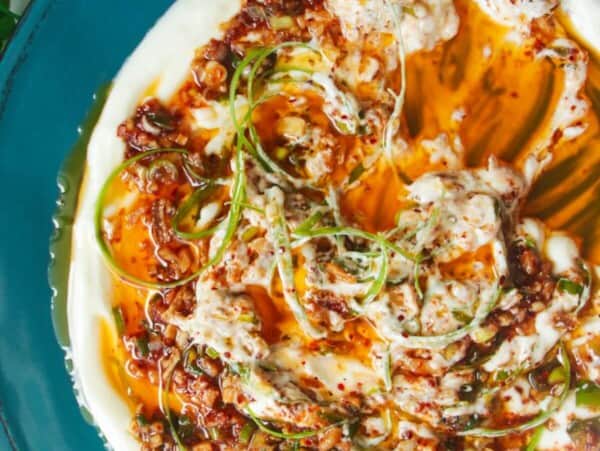 Sizzling oil on top of creamy Greek yogurt on a teal plate.