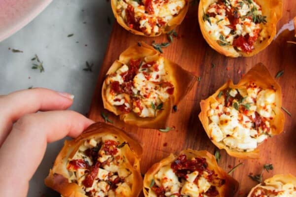 Sundried tomato and feta filo cups on a small wooden board.