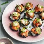 Salmon sushi cups on a pink plate, with aioli and sweet chilli on the side.