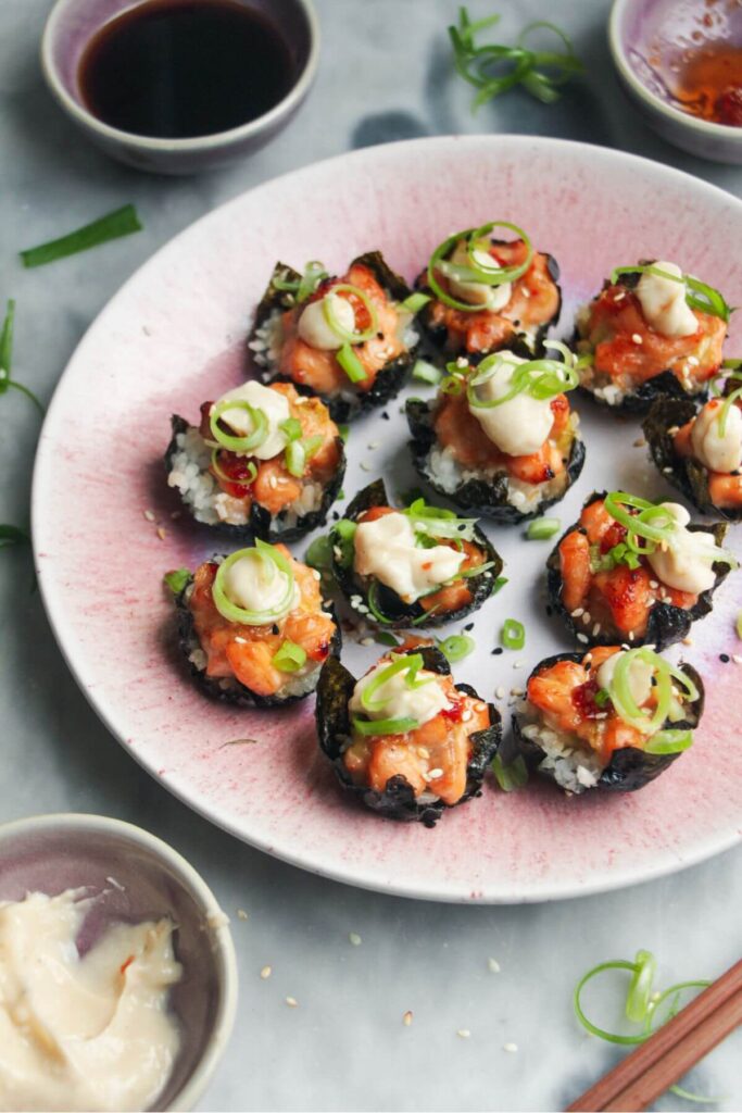 Salmon sushi cups on a pink plate, with aioli and sweet chilli on the side.