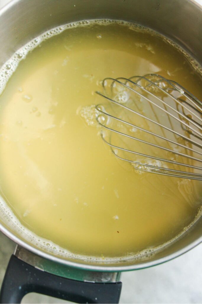 Whisking gelatin into champagne mixture in a small pot.