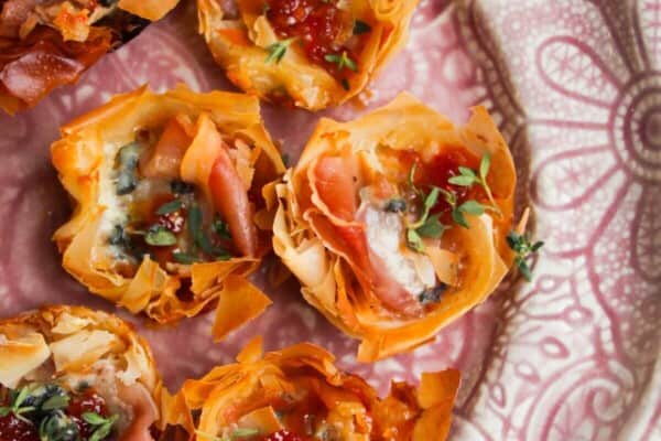 Baked blue cheese, prosciutto, sweet chilli bites on a small pink plate.