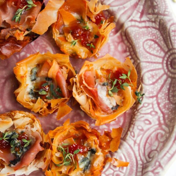 Baked blue cheese, prosciutto, sweet chilli bites on a small pink plate.