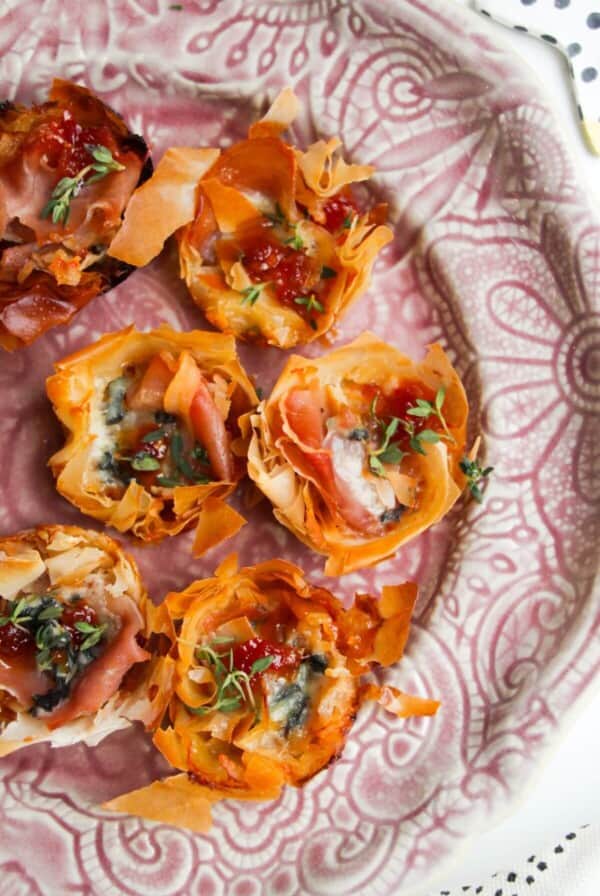 Baked blue cheese, prosciutto, sweet chilli bites on a small pink plate.