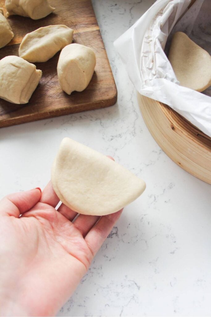 Hand holding shaped, folded bao.