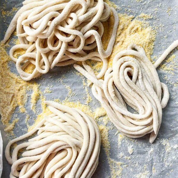 Pici pasta nestled on a lined baking tray.