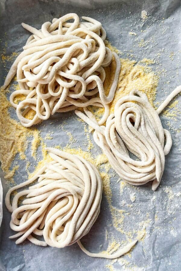Pici pasta nestled on a lined baking tray.