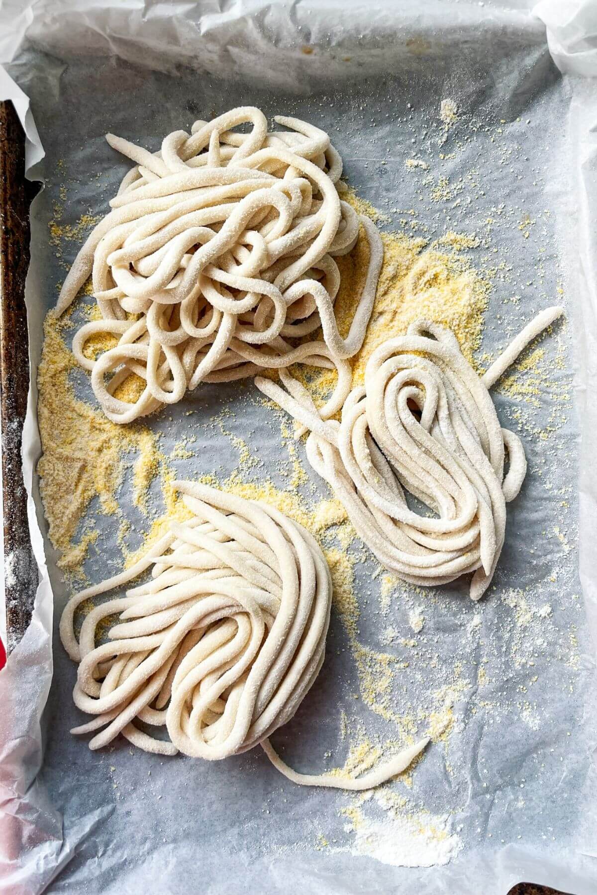 Pici pasta nestled on a lined baking tray.