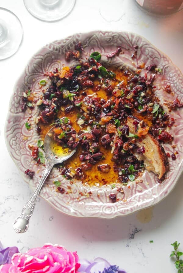 Date night bread dipping oil on a pink plate with a silver spoon.