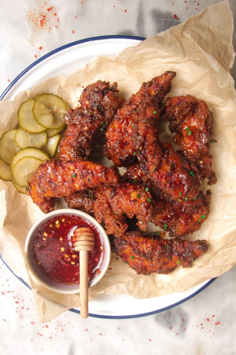 Plate of crispy hot honey chicken tenders with hot honey sauce on the side.