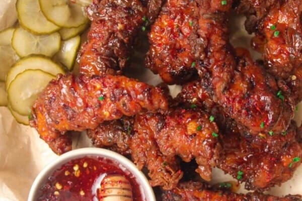Plate of crispy hot honey chicken tenders with hot honey sauce on the side.