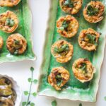 Jalapeno popper taco cups on a green rectangular plate, with a bowl of jalapenos on the side.