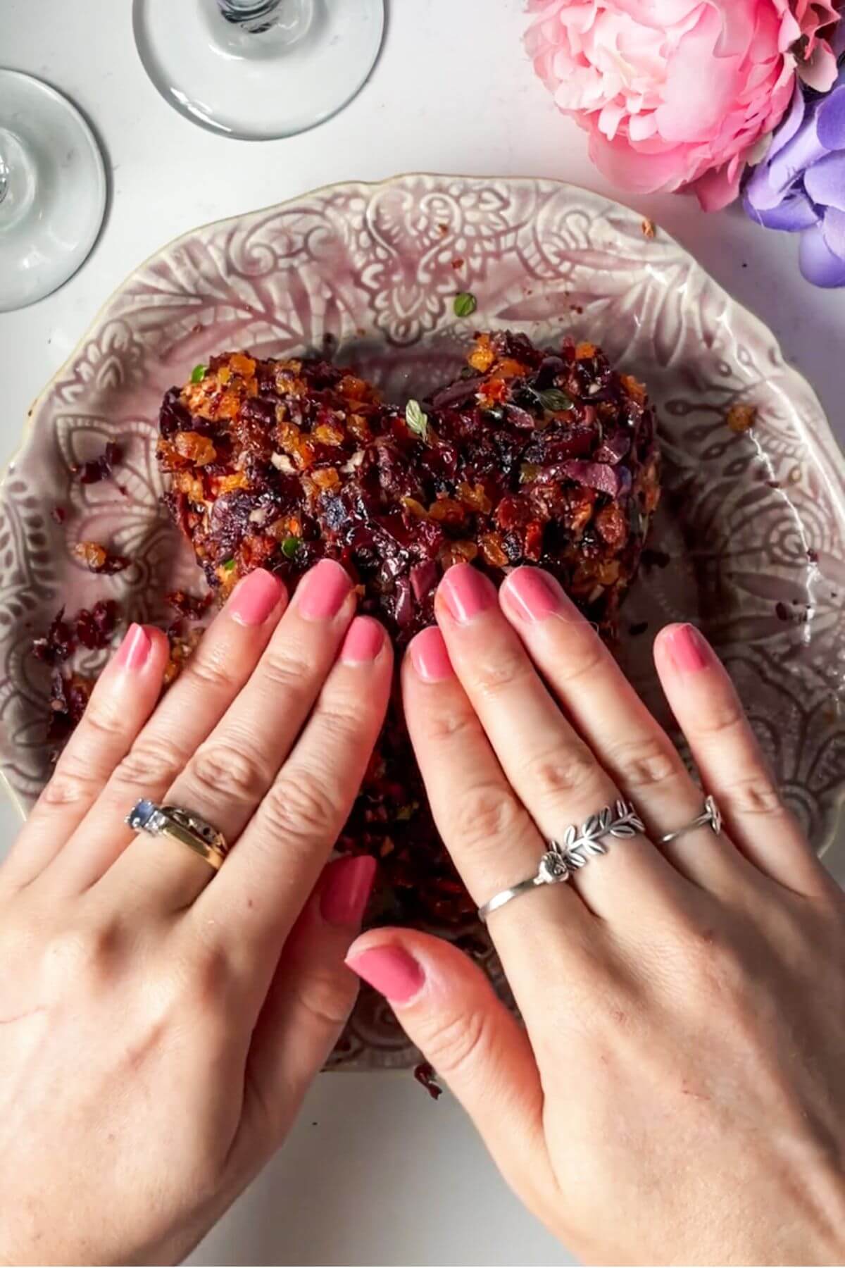 Hands pressing topping into cheese heart on a small plate.