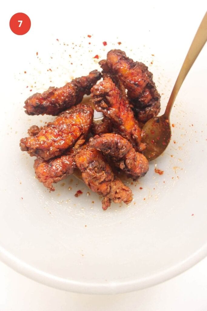 Fried chicken tenders in a bowl, tossed with hot honey sauce.