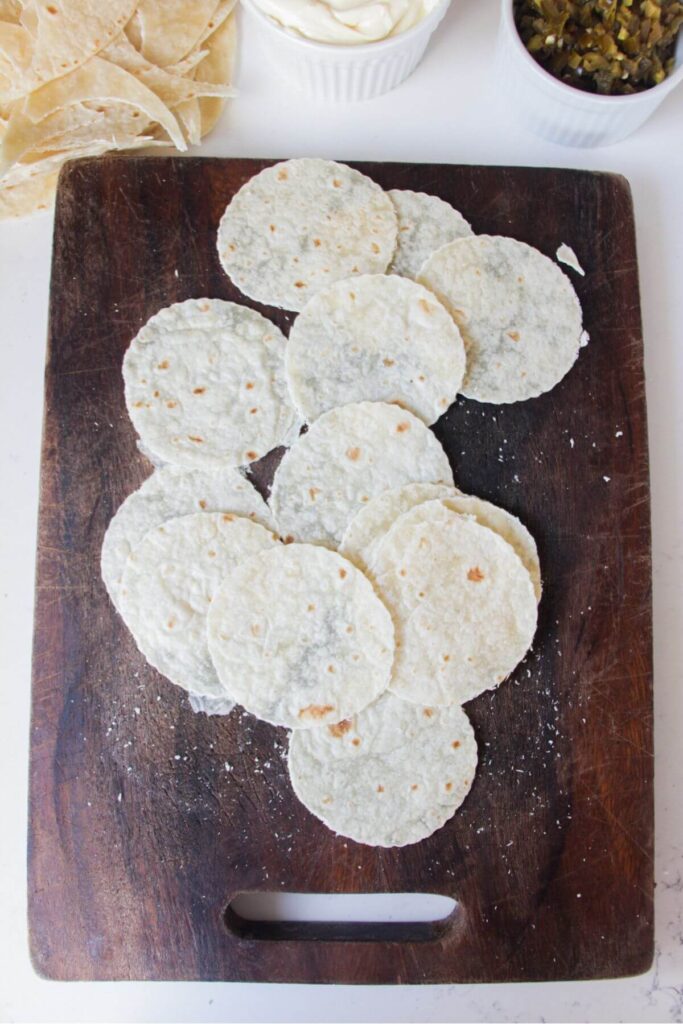 Mini tortilla circles on a wooden board.