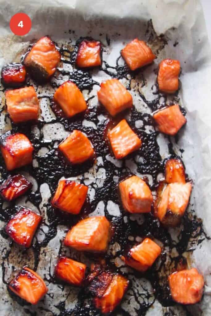 Charred baked salmon pieces on a sheet pan.