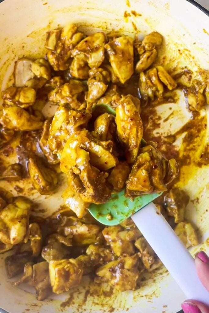 Cooked, spiced chicken pieces on a rubber spatula.