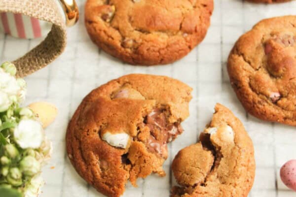 Mini egg cookies on baking paper, with more mini eggs on the side.