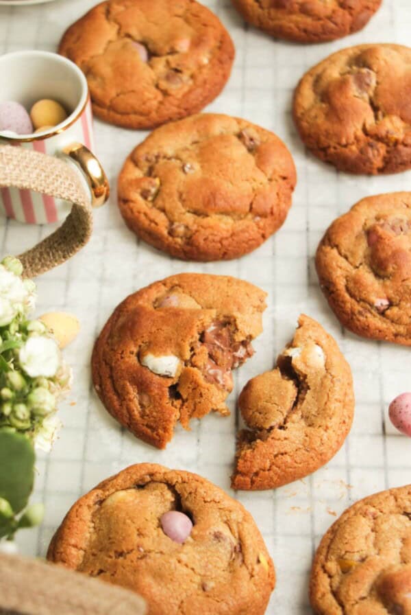 Mini egg cookies on baking paper, with more mini eggs on the side.