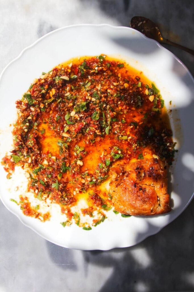 Sundried tomato dipping oil on a white plate with bread on the side.