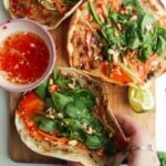 Three chicken banh mi tacos on a wooden board.