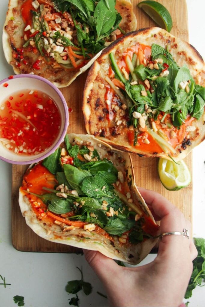 Three chicken banh mi tacos on a wooden board.