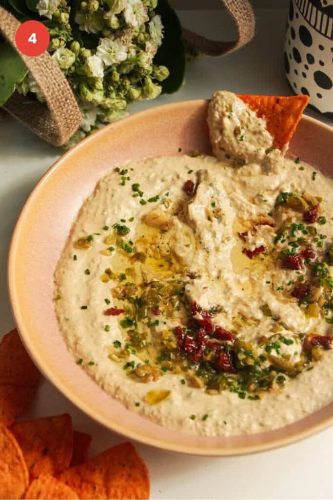Tortilla chip in whipped cottage cheese dip in a serving bowl.