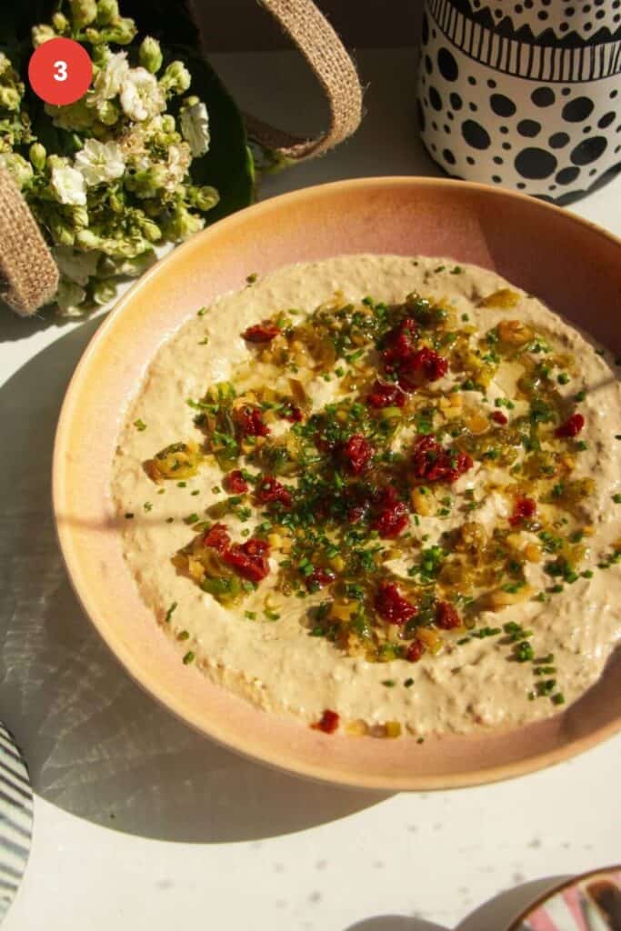 Cottage cheese dip topped with jalapenos and sundried tomatoes in a bowl.