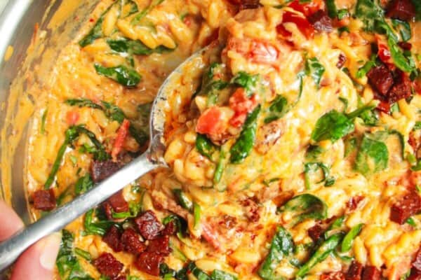 Creamy Marry Me orzo in a stainless steel pan with a silver spoon.