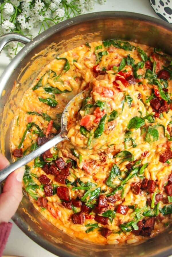 Creamy Marry Me orzo in a stainless steel pan with a silver spoon.