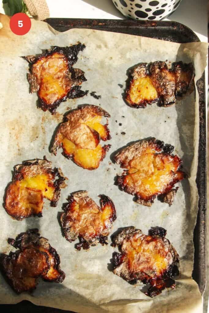 Crispy smashed potatoes on a parchment paper lined baking sheet.