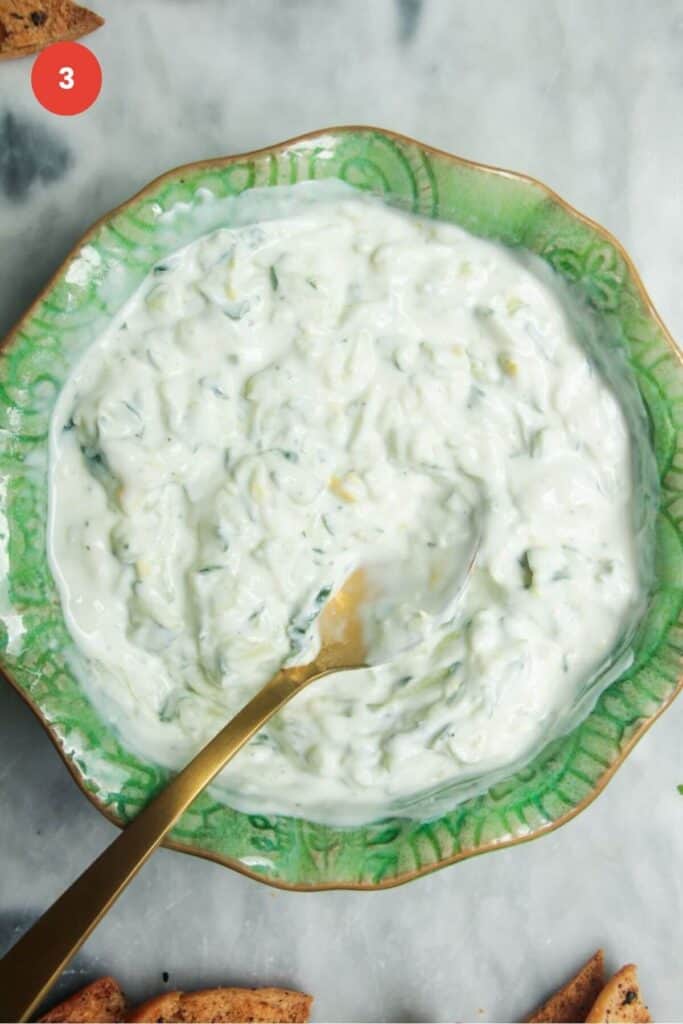 Spoon in a bowl with tzatziki sauce.