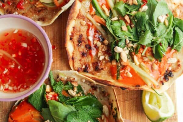 Three chicken banh mi tacos on a wooden board.