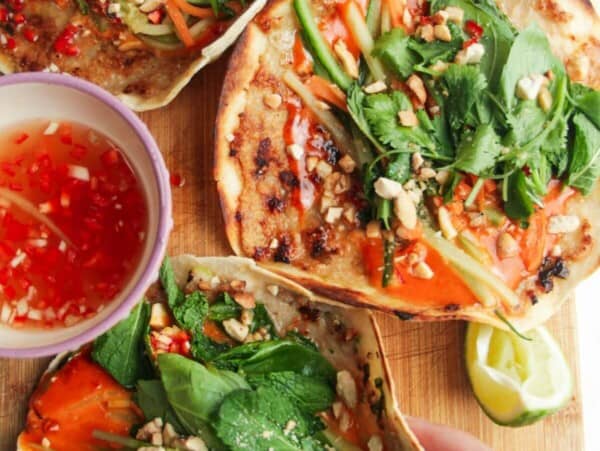 Three chicken banh mi tacos on a wooden board.