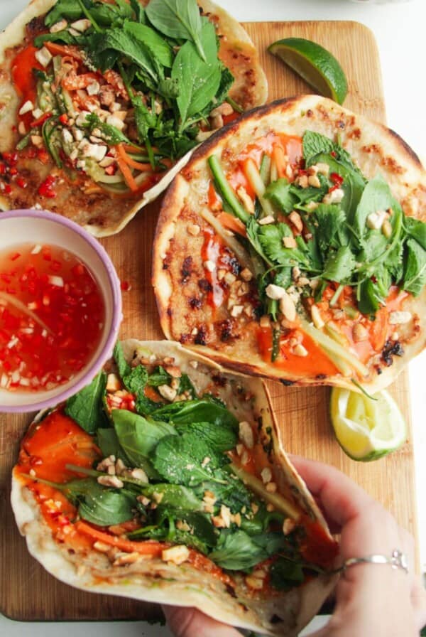Three chicken banh mi tacos on a wooden board.