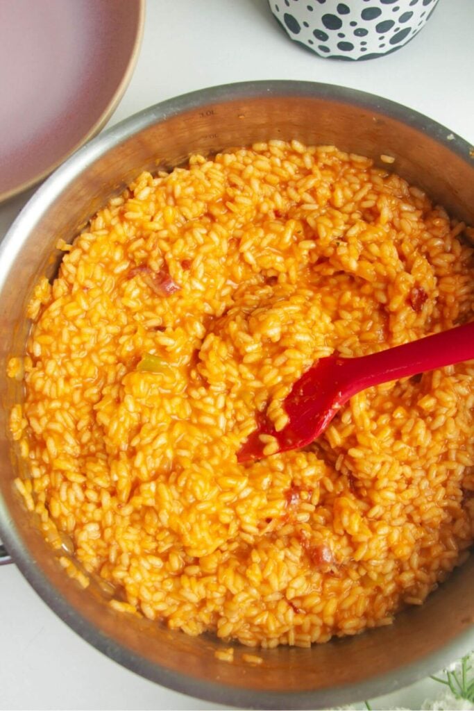 Gochujang risotto stirred with a spatula in a large pan.