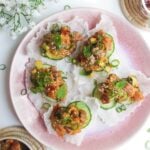Five tuna rice paper cups on a pink plate.
