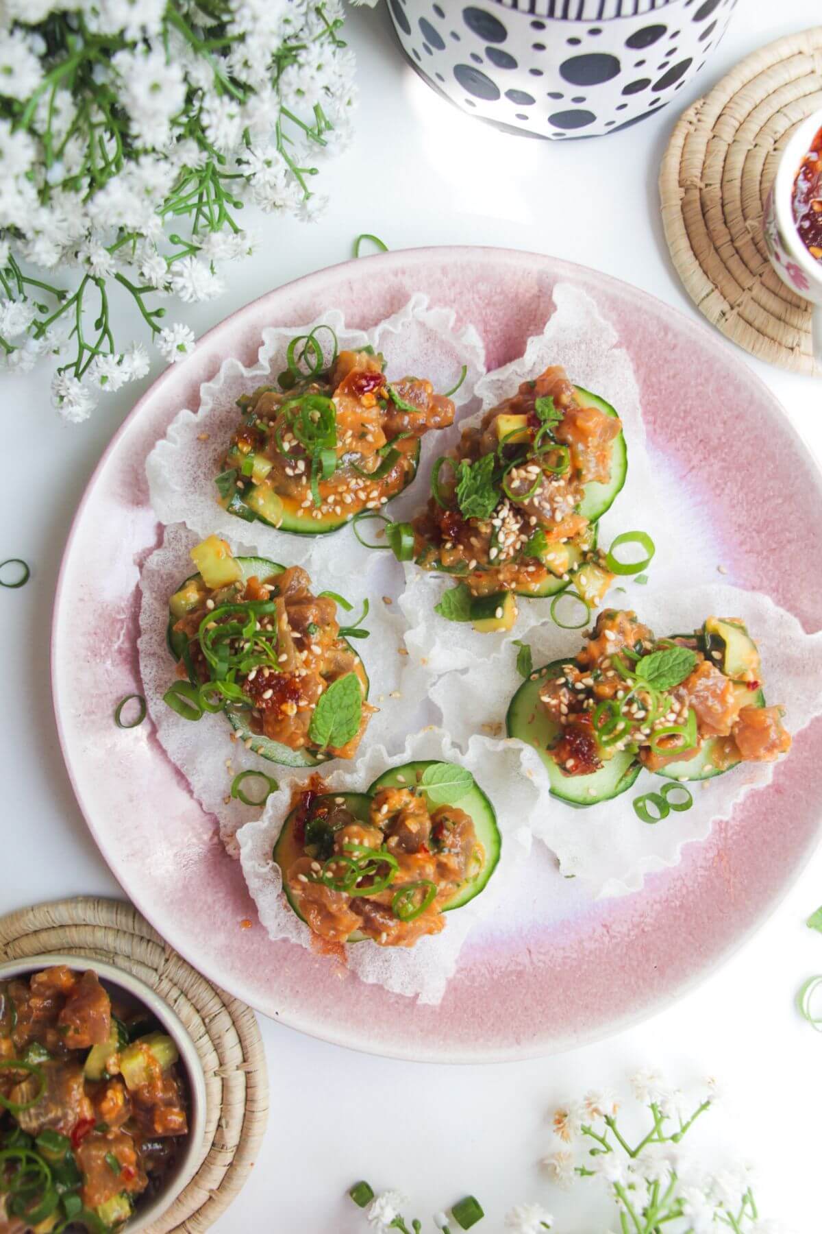 Five tuna rice paper cups on a pink plate.