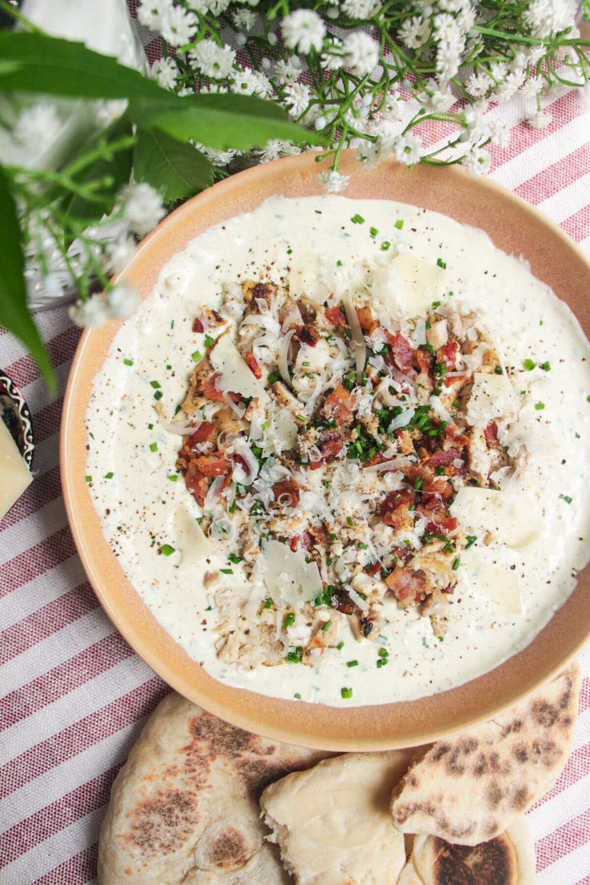 Chicken Caesar dip mixed and topped with extra chicken and bacon.