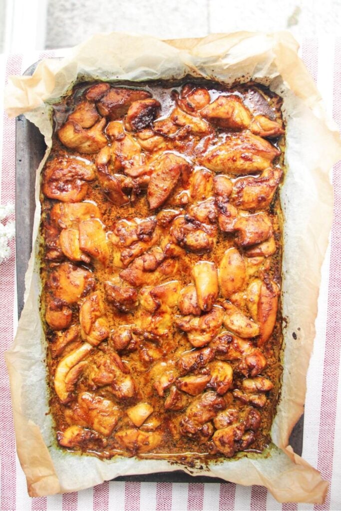 Charred chicken pieces in a lined oven tray.