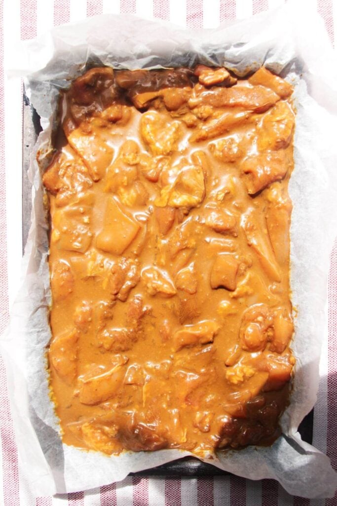 Marinated chicken satay pieces in a lined oven tray.
