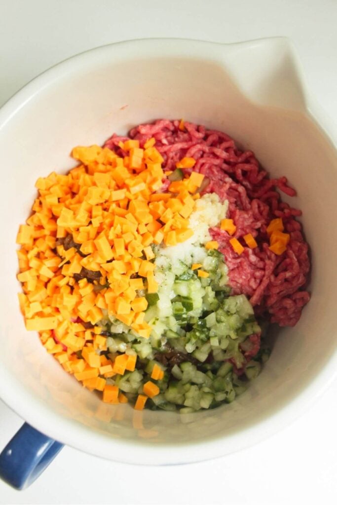 Cheese, pickles, ground beef in a mixing bowl.