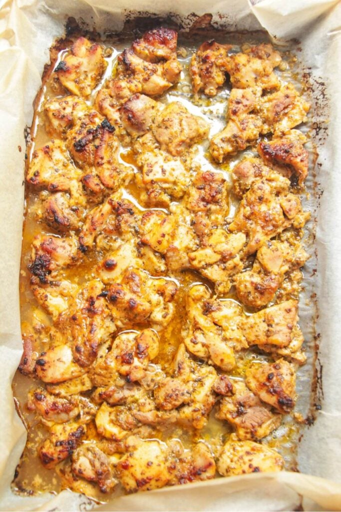 Charred, cooked chicken on a lined oven tray.