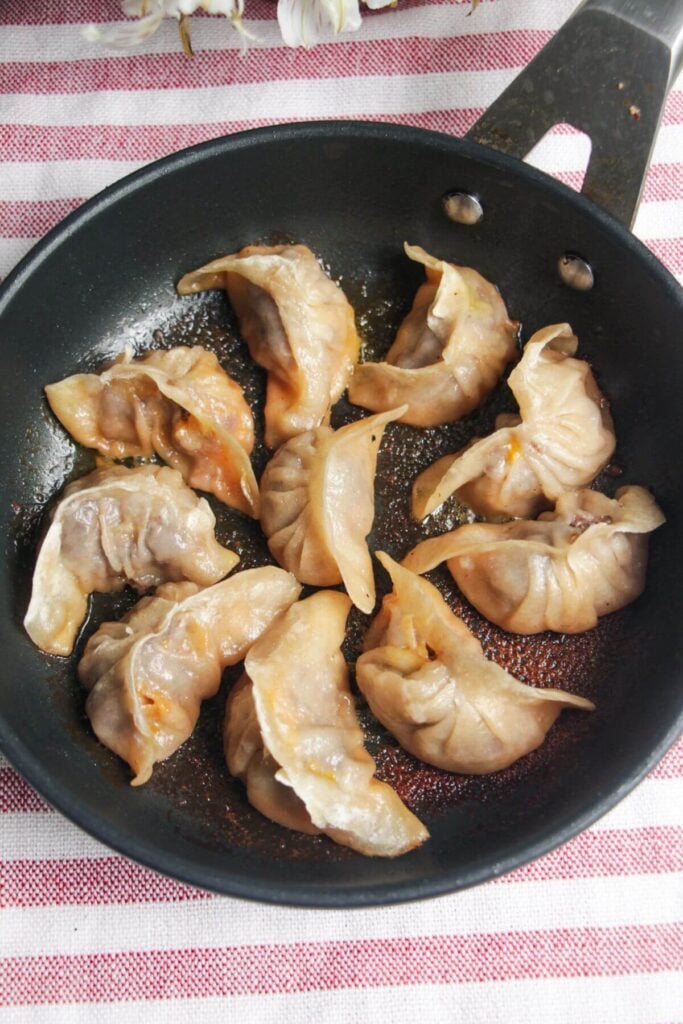 Crispy pan-fried cheeseburger dumplings in a small pan.
